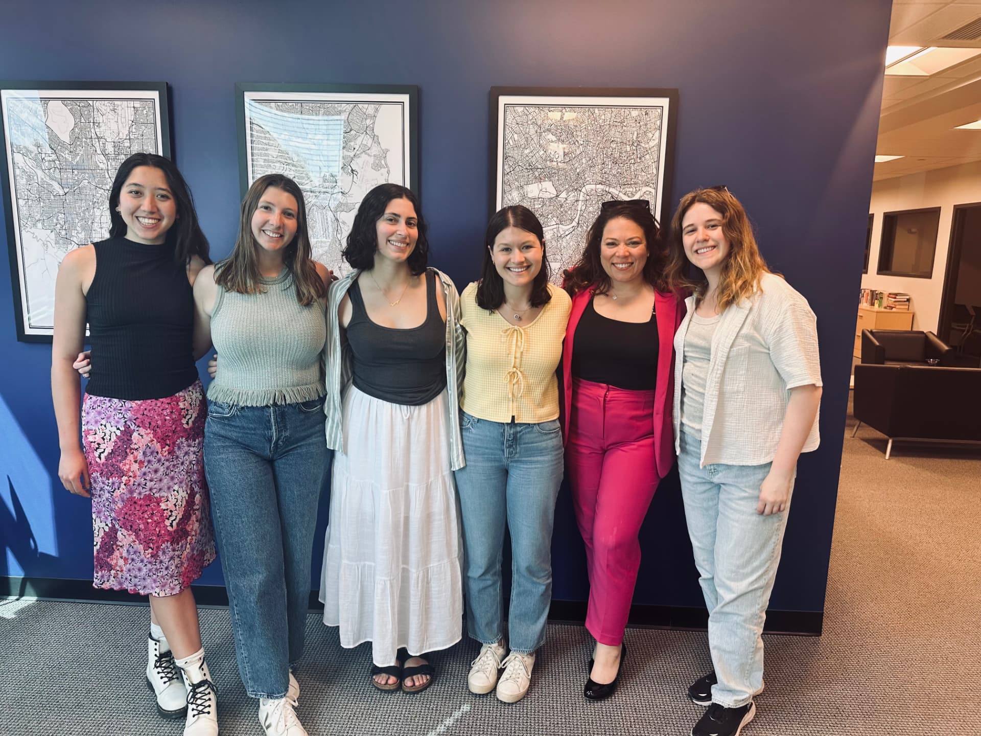 A group of young women smiling together in an office hallway