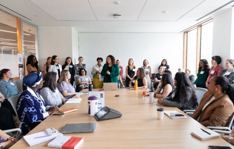 A diverse group of women gathered around a conference table for a leadership session
